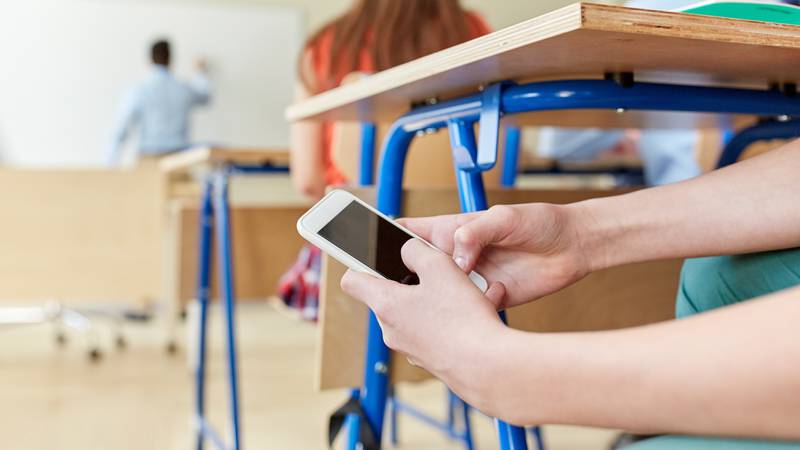 education, high school, learning, technology and people concept - student boy hands with smartphone texting on lesson