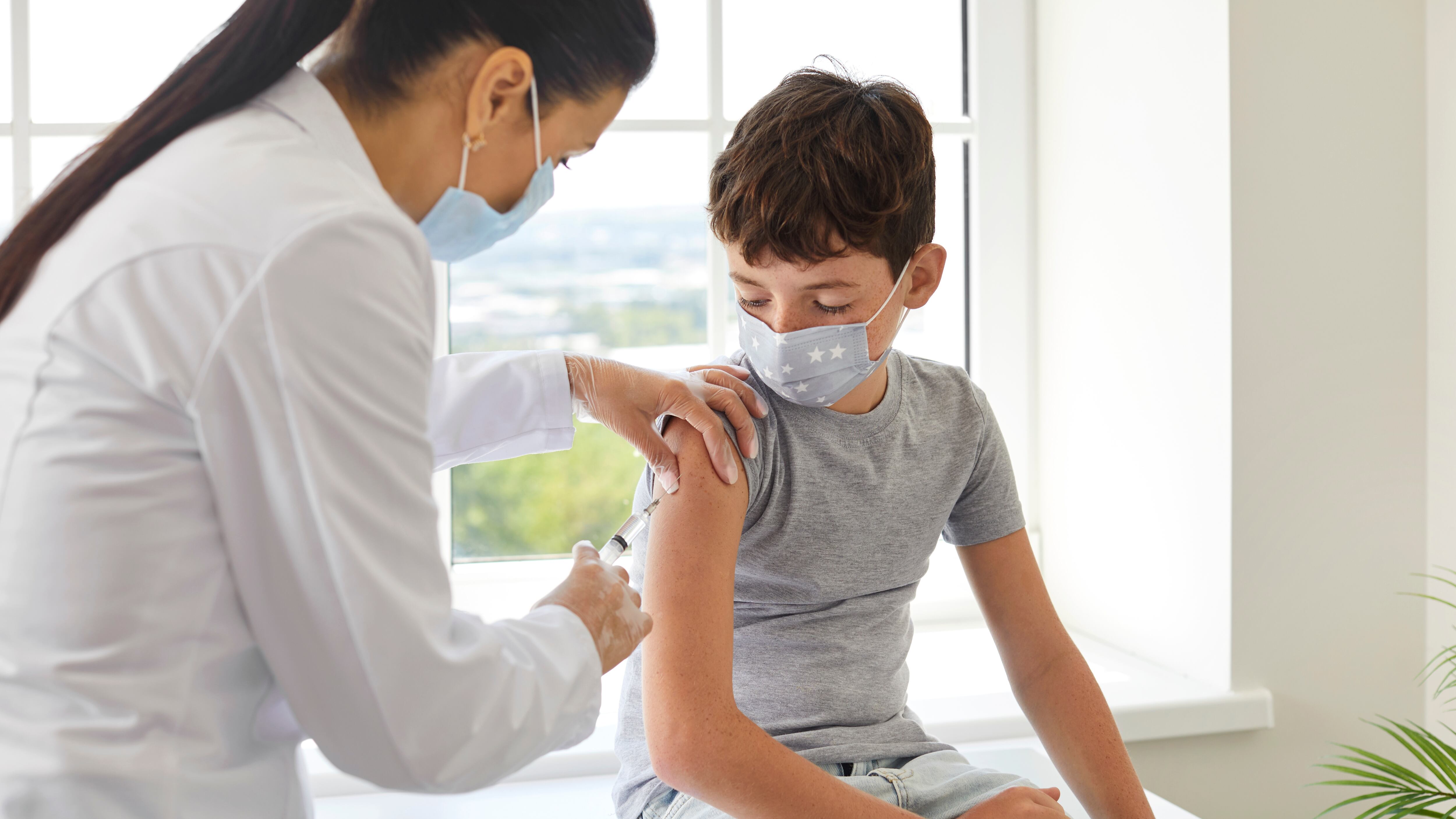 Nurse or doctor gives shoulder injection to little boy